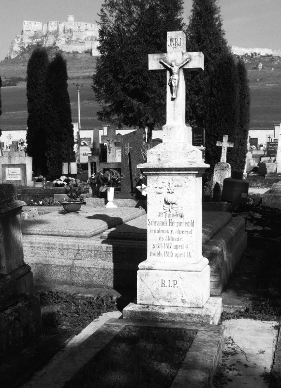 Hrob řádového lékárníka H. Schramka na hřbitově ve Spišském Podhradí; na náhrobku je patrný řádový znak – granátové jablko s křížem a hvězdou, obsahuje nápis v maďarštině, v překladu: „Zde odpočívá Hermenegild Schramek, subprior a kněz Milosrdných bratří, nar. 4. dubna 1817, zemř. 18. dubna 1895,“ a zkratku R.I.P. – requiescat in pace/ať odpočívá v pokoji (foto: autorka)